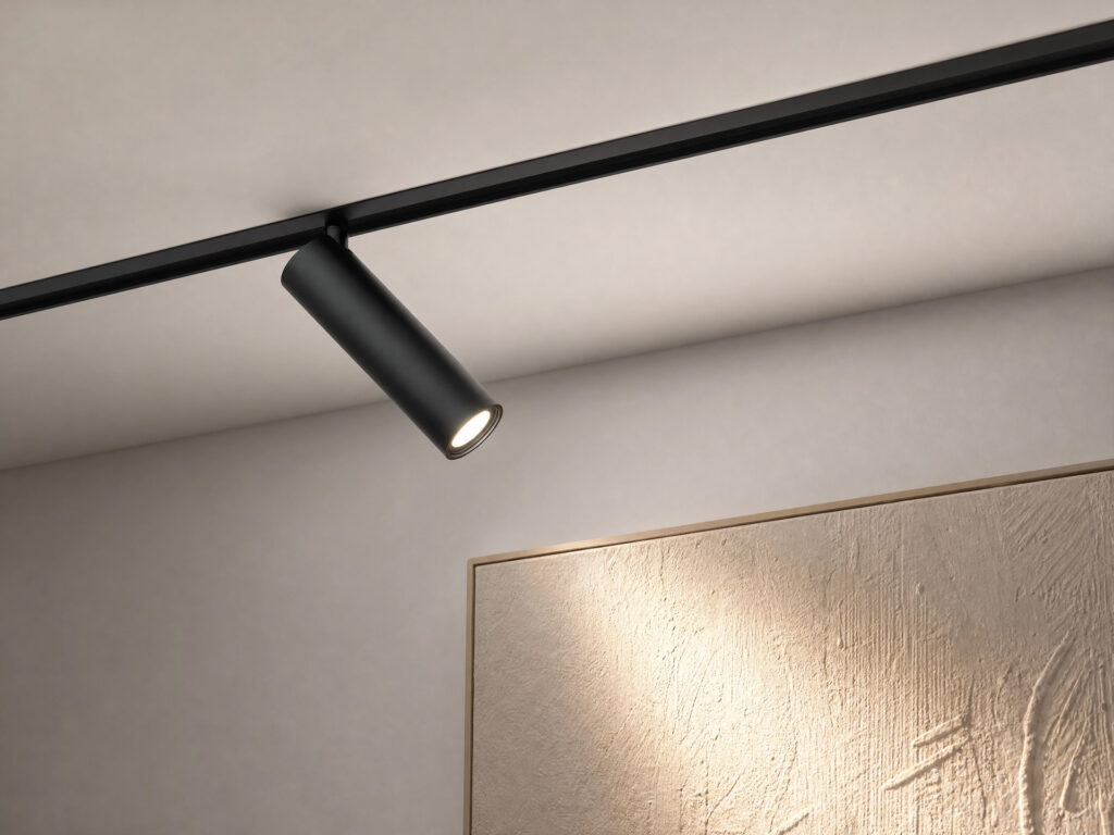 Close-up of a sleek, minimalist black track lighting fixture precisely illuminating a textured canvas artwork.