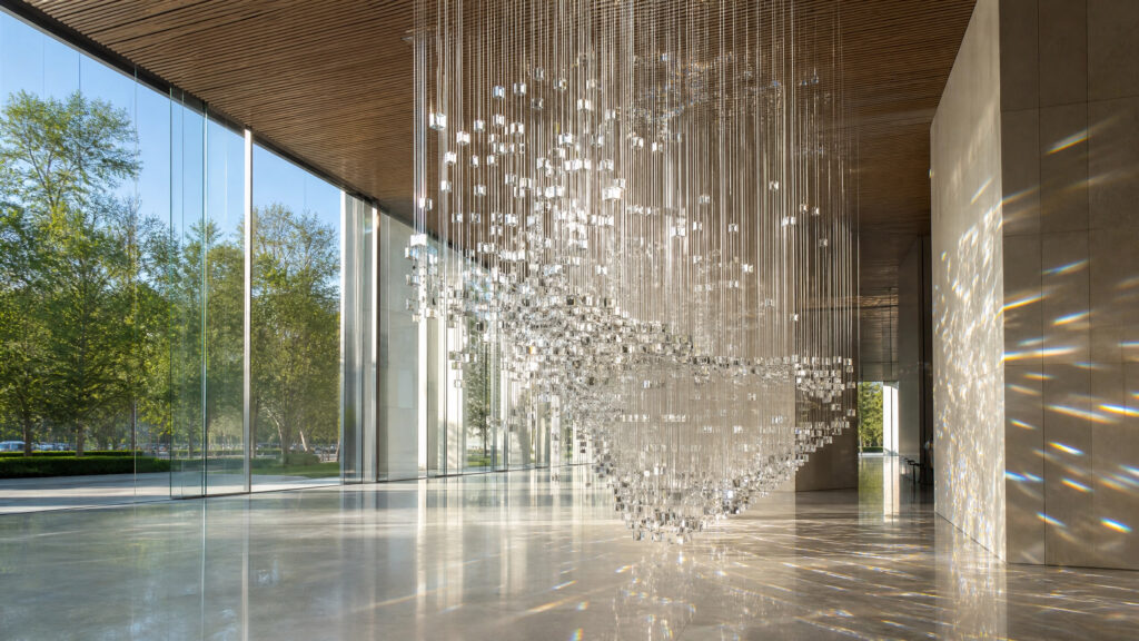Contemporary art installation within a glass-walled architectural space, interacting with natural light.
