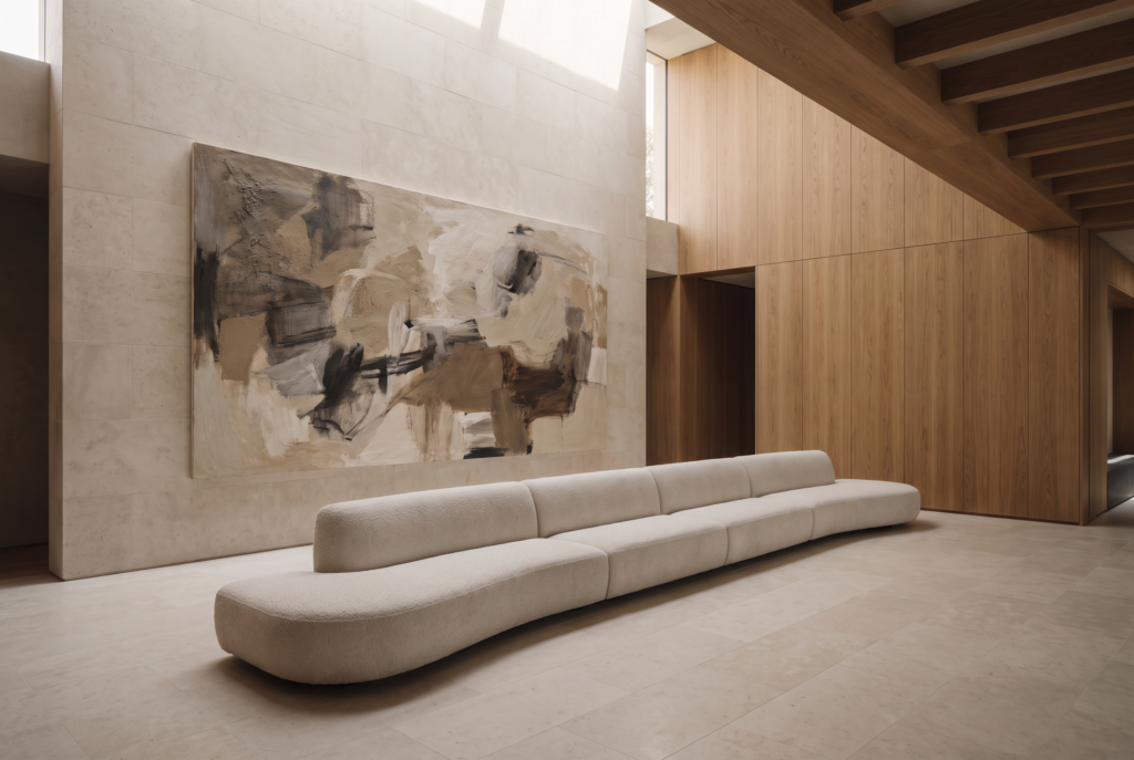 An oversized minimalist artwork balanced above a long sculptural sofa in a spacious interior.