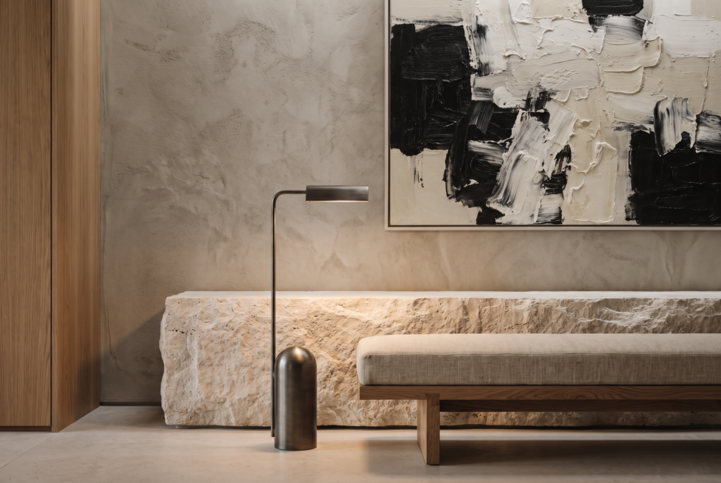 A minimalist artwork surrounded by textured plaster, travertine stone, oak, brushed metal, and linen.